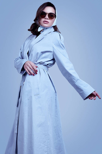 Young elegant brunette woman in coat and shawl posing in studio - 写真・画像