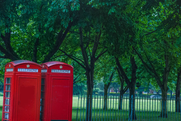 Estilo vintage de cabinas telefónicas rojas típicas en la calle lluviosa en
 - Foto, Imagen