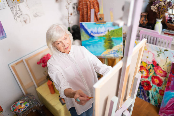 Top view of famous aged artist working in her workshop - Fotó, kép