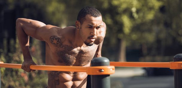 Muscular Guy fazendo Street Workout, Exercício em barras paralelas
 - Foto, Imagem