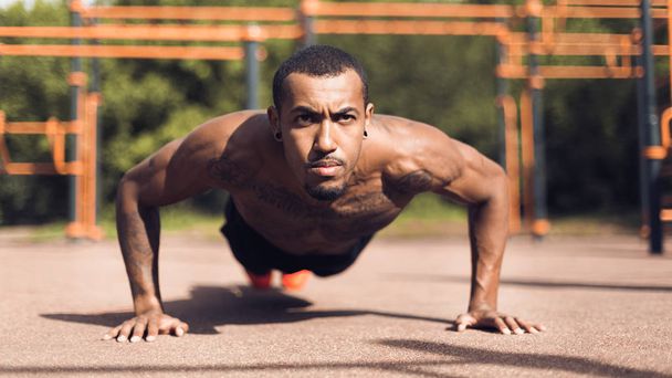 Hombre muscular haciendo push ups en terreno deportivo
 - Foto, Imagen