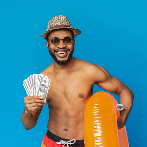 Счастливый африканский мужчина с кучей денег и надувным кольцом
 - Фото, изображение