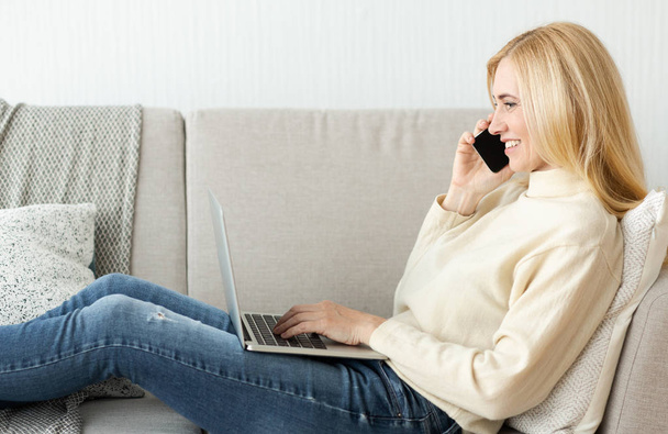 Kobieta rozmawiająca przez telefon, korzystająca z laptopa - Zdjęcie, obraz