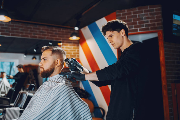 Stylish man sitting in a barbershop - Foto, Bild