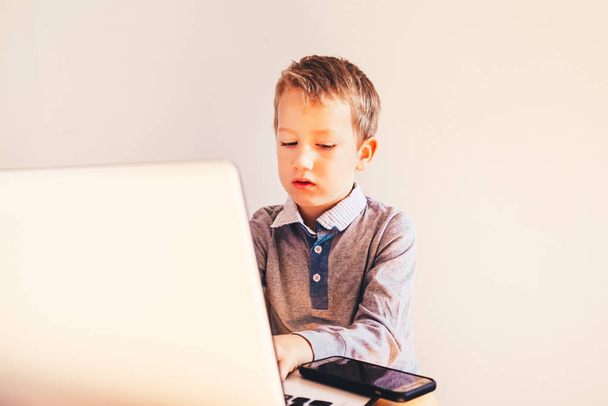 Bambino con viso molto espressivo di fronte a un computer portatile con rabbia
  - Foto, immagini