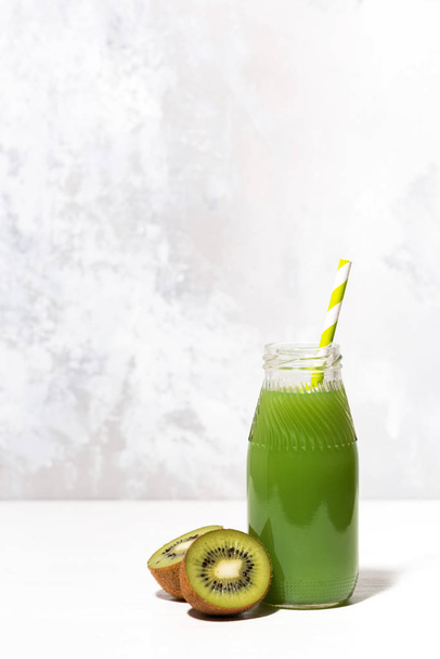 green kiwi juice in a bottle on white background, vertical - Foto, imagen