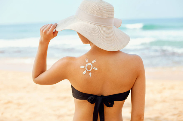 Beautiful Woman in Bikini Applying Sun Cream on Tanned  Shoulder. Sun Protection. Skin and Body Care. Girl Using Sunscreen to Skin. Portrait Of Female Holding Suntan Lotion and Moisturizing Sunblock. - Photo, Image