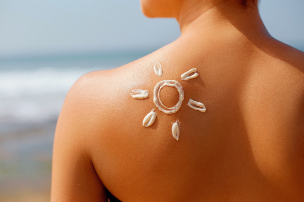 Portret van prachtige vrouw in bikini met de getekende zon op een schouder op strand - Foto, afbeelding