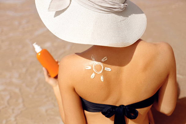 Bőrápolás. Napvédő. Gyönyörű nő bikini alkalmazni napkrémet Face. A nő suntan Lotion a strandon. Portré női Holding hidratáló Sunblock. A lány használja napvédő a bőre. - Fotó, kép