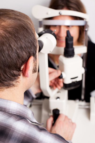 Optician Testing Patient's Eyes In Examination Room - Foto, imagen