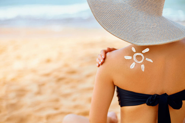 Woman putting sunblock lotion on shoulder before tanning during summer holiday on beach vacation resort - Zdjęcie, obraz