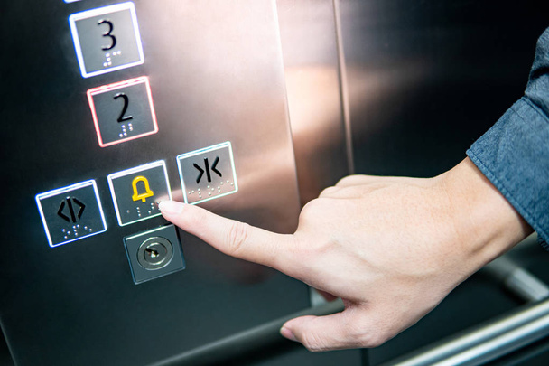 Mano masculina presionando el botón de emergencia en ascensor
 - Foto, Imagen