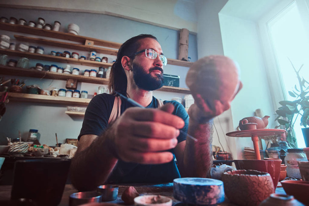 Pensive entusiastici Fazekas a szemüveg saját műhely működő egy új kézzel készített teáskanna. - Fotó, kép