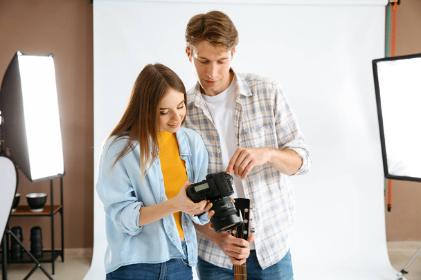 Professional photographer showing pictures to model in studio - Photo, Image
