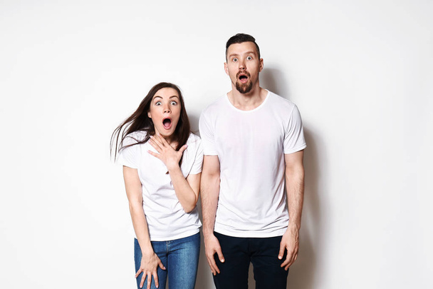 Shocked young couple on light background - Foto, imagen