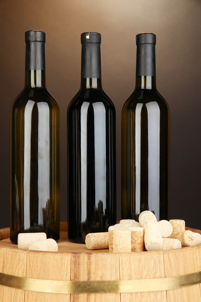 Wine and corks on barrel on brown background - Foto, imagen