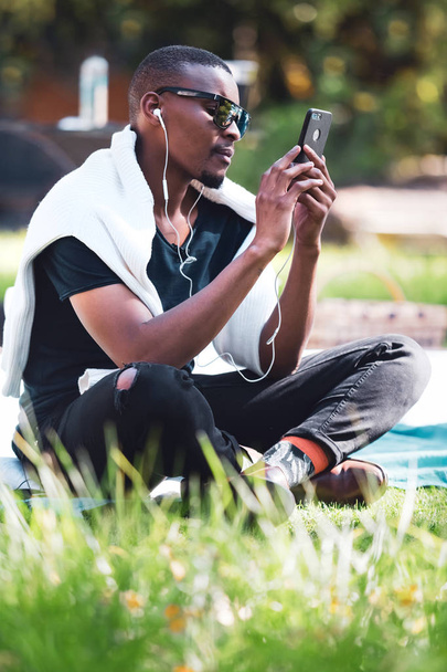 Ciudad del Cabo, Sudáfrica, 11 de mayo - 2019: Hombre sentado en el parque y mirando el teléfono
. - Foto, imagen