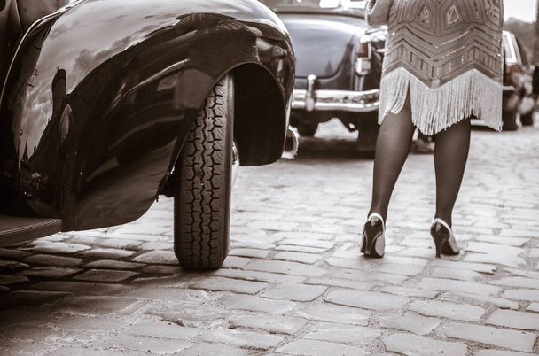 Piernas de mujer saliendo de auto viejo. Mujer joven en zapatos de tacón alto
. - Foto, imagen