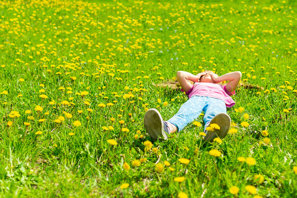 Mała dziewczynka leży na zielonej łące w świeżej trawie. Koncepcja lato. Selektywne skupienie. Kopiuj przestrzeń. Widok z góry - Zdjęcie, obraz
