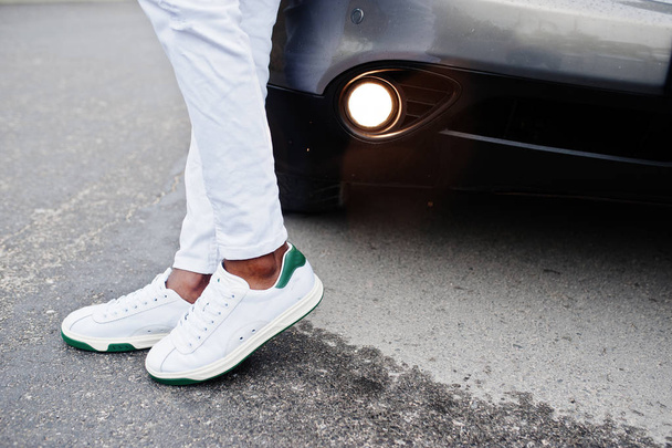 Close-up sneakers in Afrikaanse man op witte broek tegen auto. - Foto, afbeelding