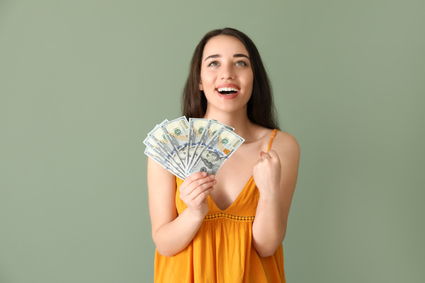 Happy young woman with dollar banknotes on color background - Photo, Image