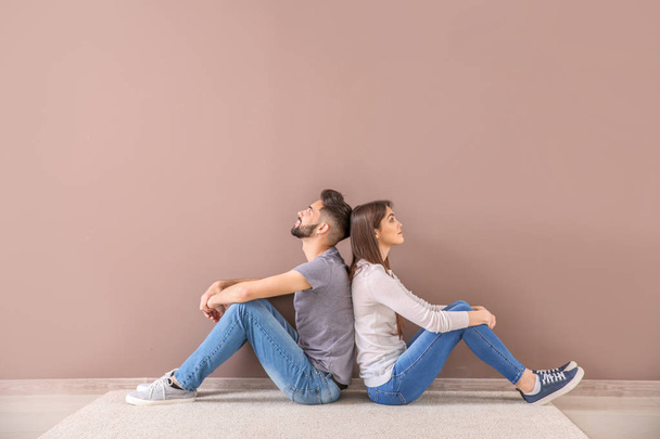 Jeune couple assis près du mur de couleur
 - Photo, image