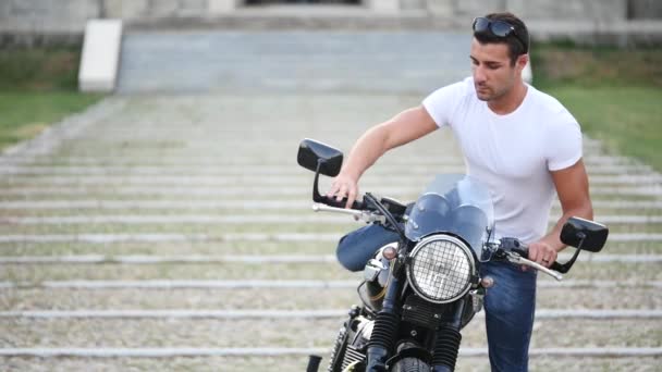 handsome sporty man wearing white t-shirt starting and riding motorcycle at sunny day    - Séquence, vidéo