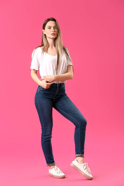 Стильна молода жінка в джинсах на кольоровому фоні
 - Фото, зображення