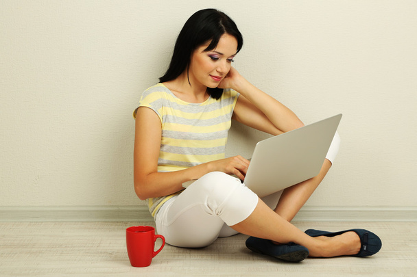 Beautiful young woman sitting with notebook in room - Photo, image
