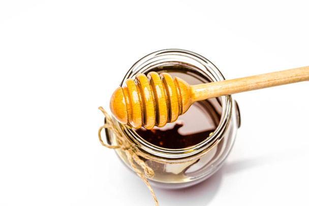 Honey dipper and glass jar of honey isolated on white background - Foto, afbeelding
