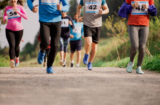 Sección media de un gran grupo de personas corriendo una competición de carreras en la naturaleza
. - Foto, imagen