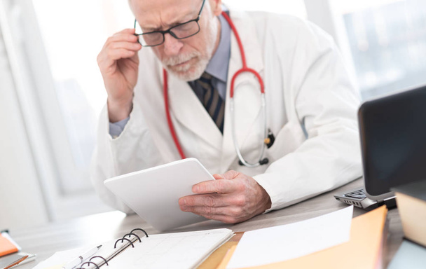 Чоловік старший лікар використовує цифровий планшет
 - Фото, зображення