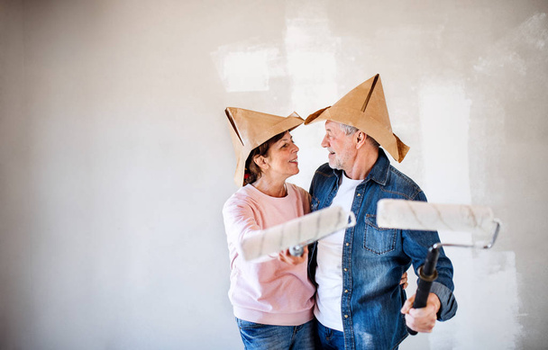 Senior couple painting walls in new home, having fun. Relocation concept. - Foto, Imagem