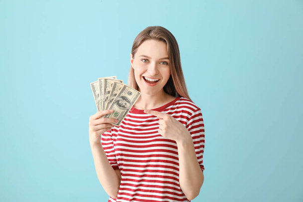 Happy young woman with money on color background - Foto, Imagen
