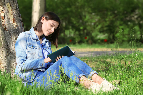Gyönyörű fiatal nő olvas könyvet a parkban - Fotó, kép