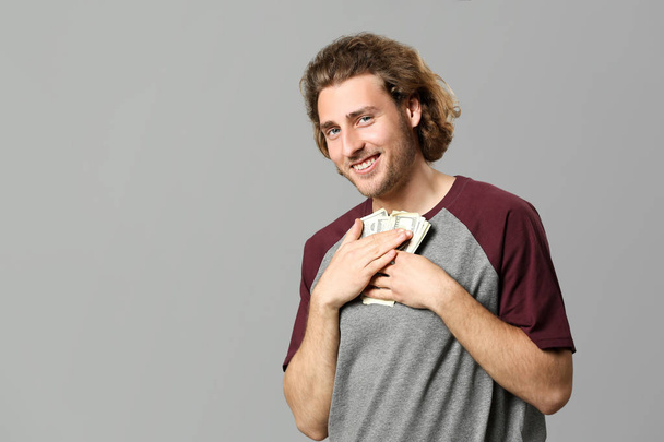Handsome man with money on grey background - Fotó, kép