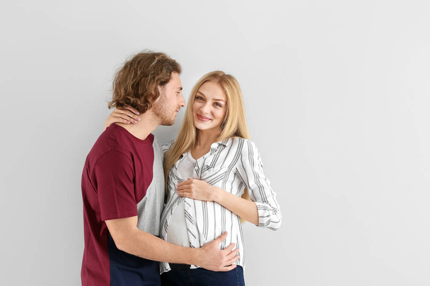 Happy young pregnant couple on light background - Фото, зображення