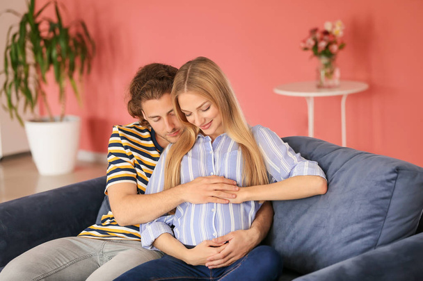 Happy young pregnant couple at home - Foto, afbeelding