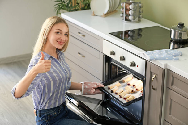 Woman taking baking tray with homemade pastry out of oven - Foto, Imagem