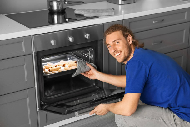 Homem levando assadeira com pastelaria caseira fora do forno
 - Foto, Imagem