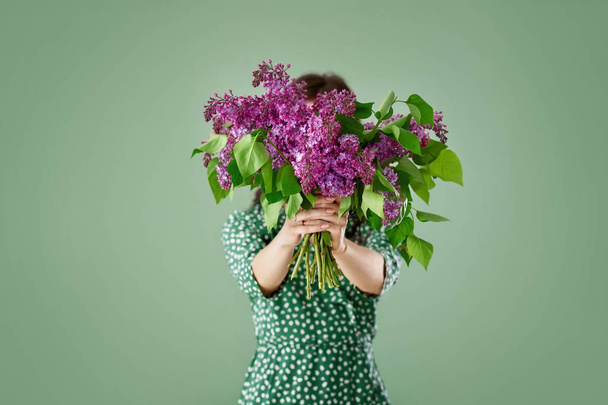 Belle jeune femme avec bouquet de fleurs lilas sur fond de couleur
 - Photo, image
