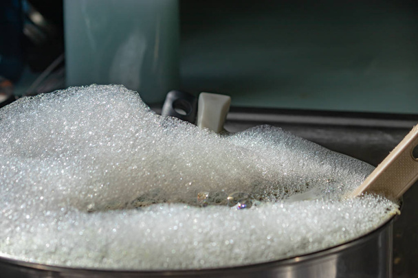 Topf voller Seifenwasser und Blasen mit Haushaltsgeräten - Foto, Bild