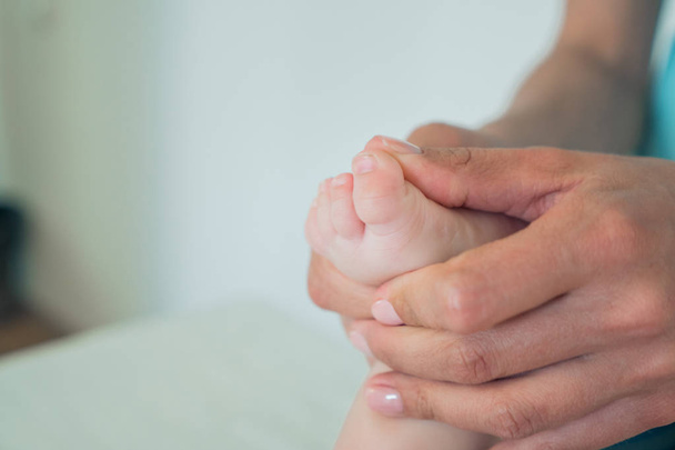 Womens hands doing foot massage to a small child close-up. Care and maintenance of a baby - Fotoğraf, Görsel