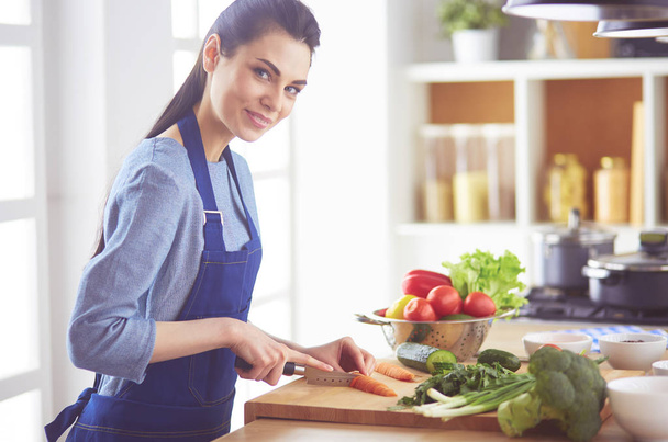 Young woman cutting vegetables in kitchen at home - Foto, Imagem
