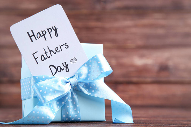 Text Happy Fathers Day with blue gift box on wooden table - Photo, Image