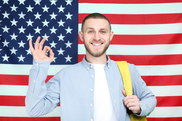 Young man with backpack on American flag background - Zdjęcie, obraz