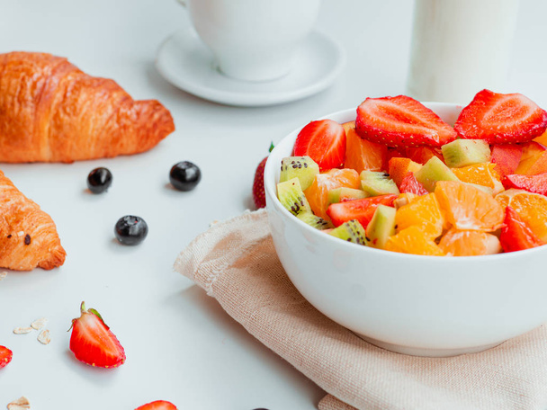 Letní snídaně s mísou zdravých čerstvých ovocných salátů, kávy, mléka a croissantů - Fotografie, Obrázek