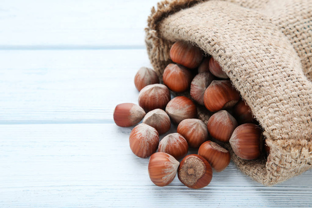 Ripe hazelnuts with sack on wooden table - Foto, afbeelding