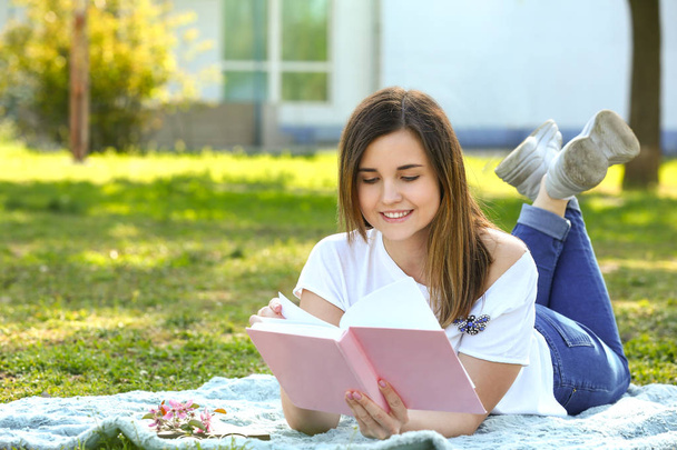 Beautiful young woman reading book in park - Foto, Imagen