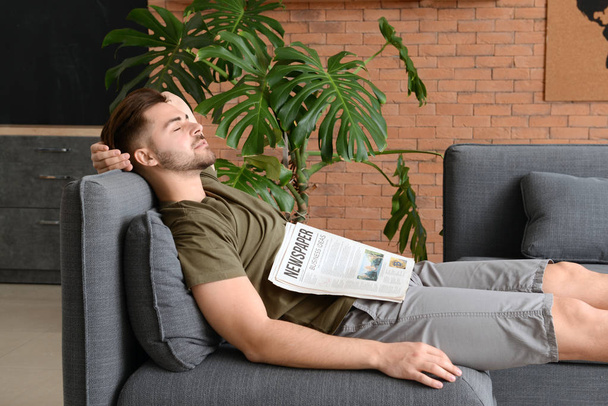 Hombre guapo con periódico durmiendo en casa
 - Foto, Imagen
